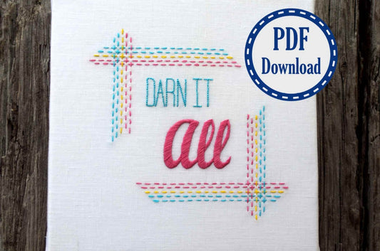 A running stitch frame and the words Darn It All embroidered in bright modern fonts and rainbow colors  on white linen, framed as a square. Digital sticker reads PDF download