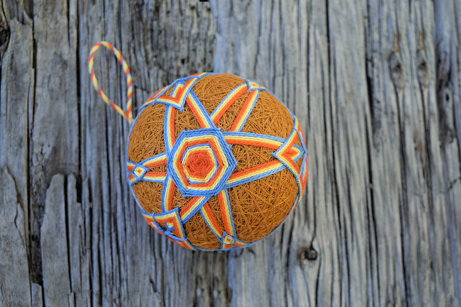 Temari ball with orange and blue hexagon pattern on gold base