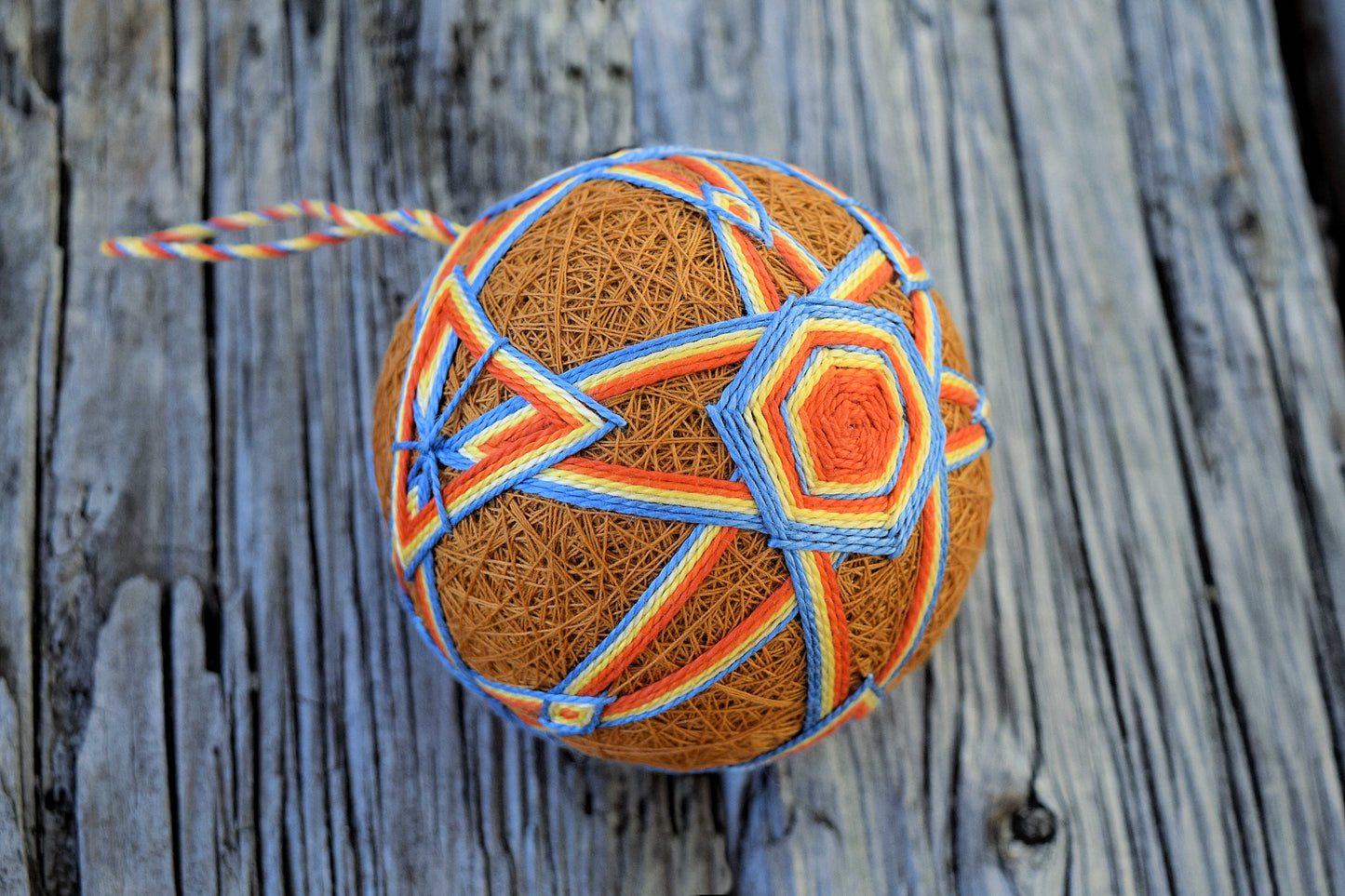 Traditional Japanese temari ball in orange and blue on wood background