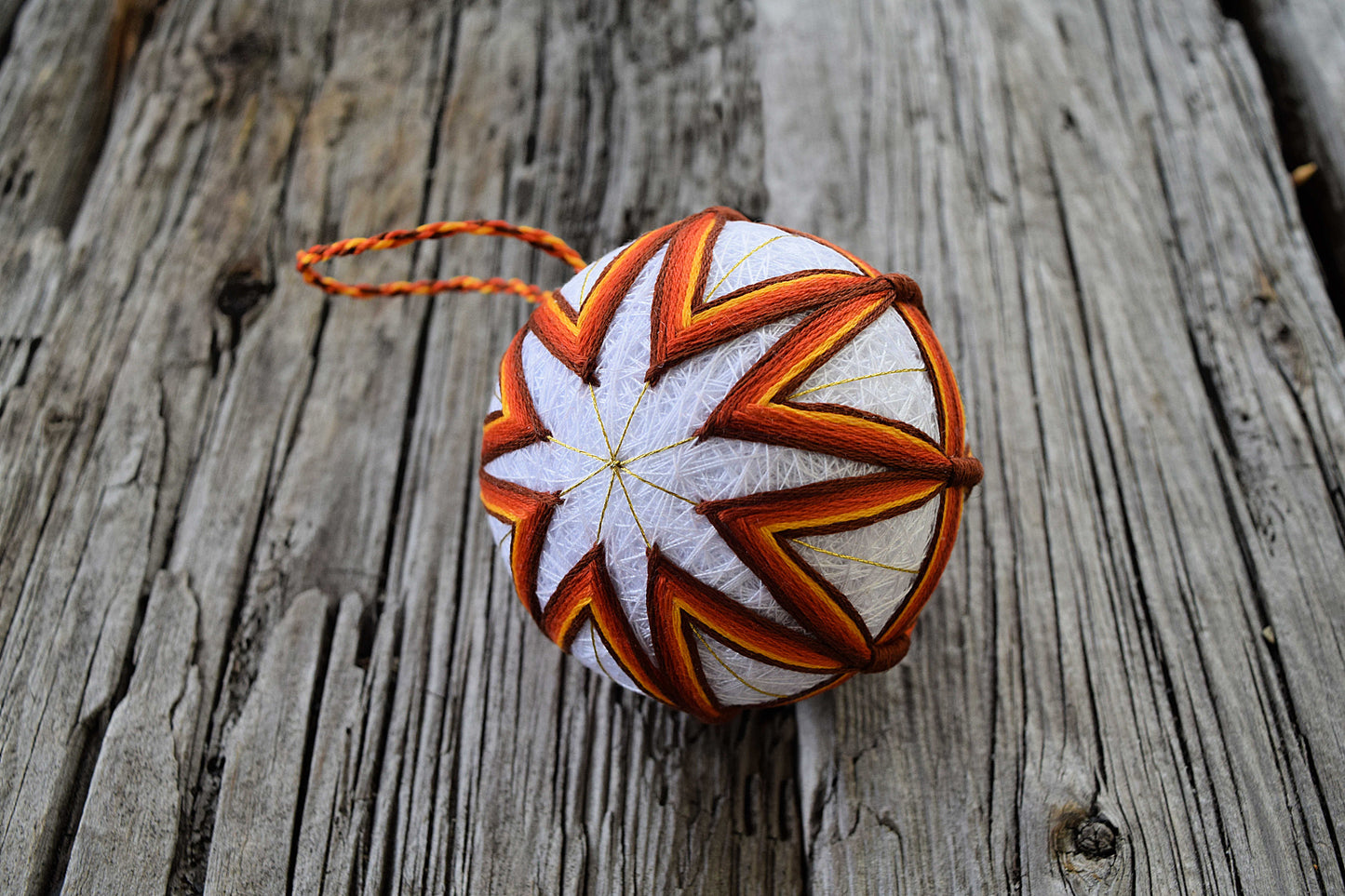 Temari ball embroidered in a star pattern in gold rust and brown