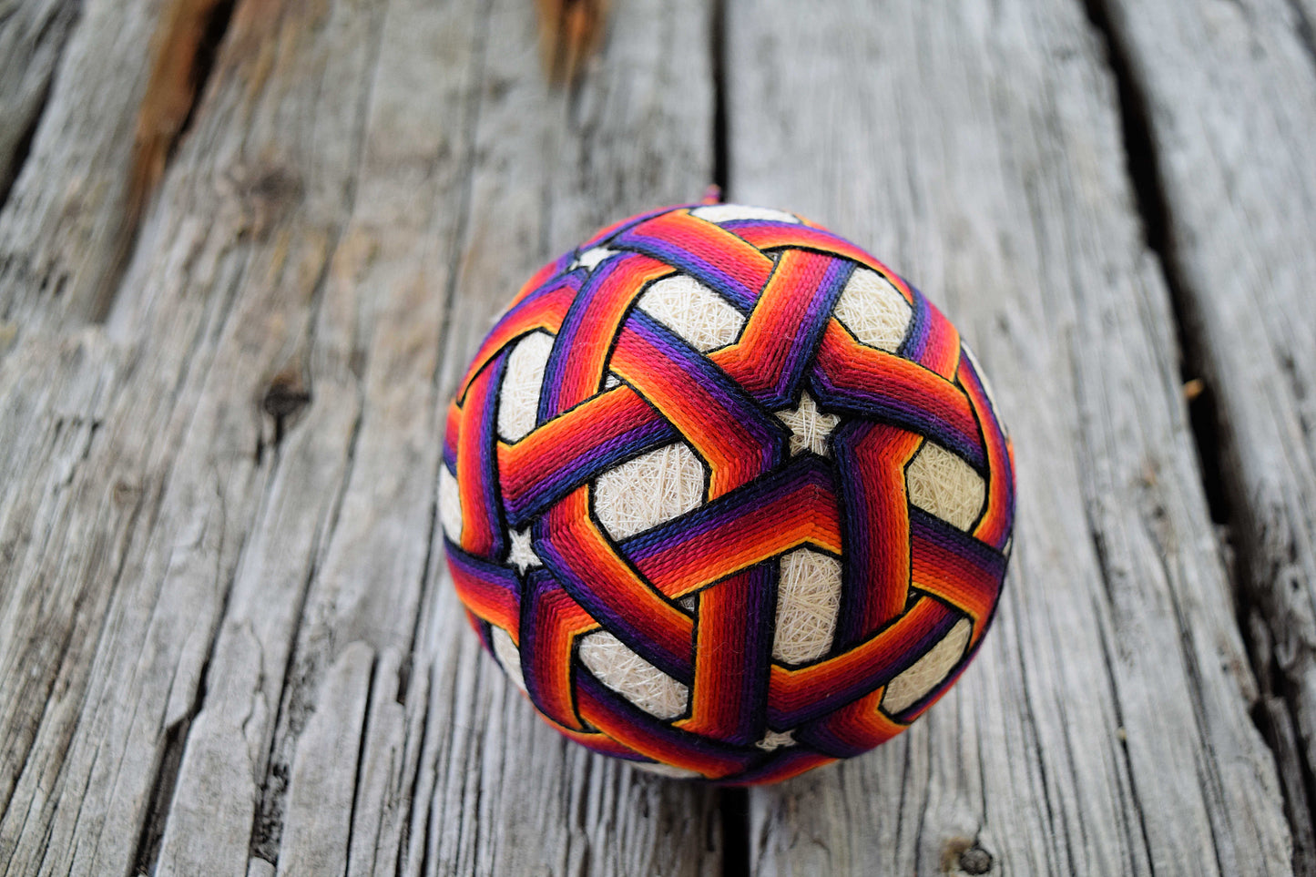 Temari ball embroidered with ombre star pattern in yellow, orange, red, purple, blue, and black