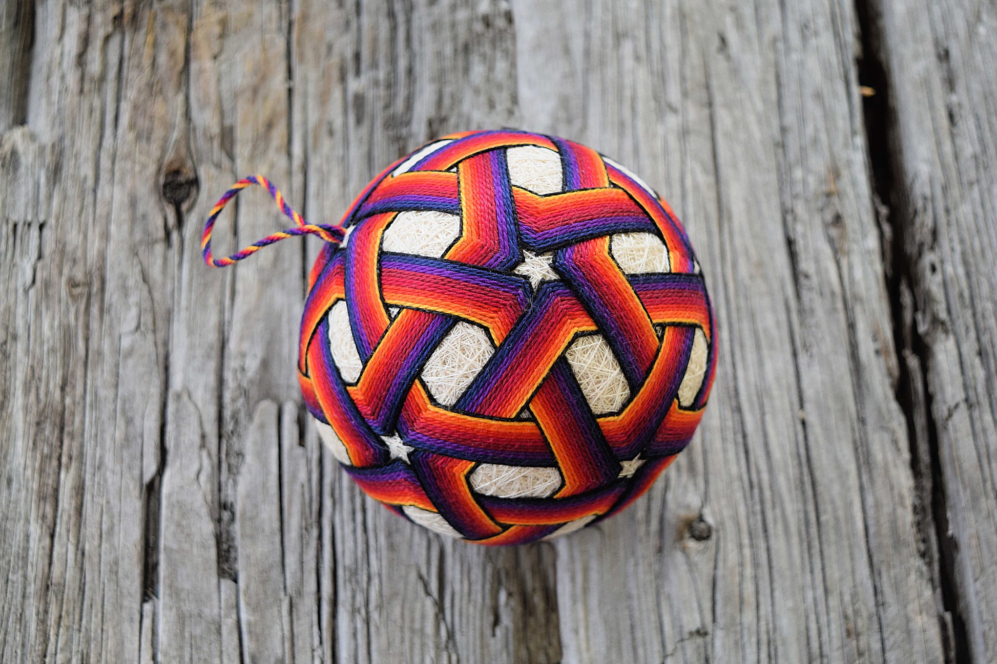 Japanese temari ball embroidered in interlacing pentagons in vibrant rainbow colors