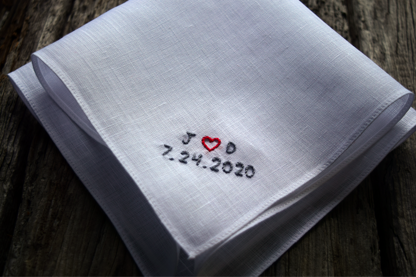 Closeup of handkerchief hand embroidered with tiny initials and wedding date 