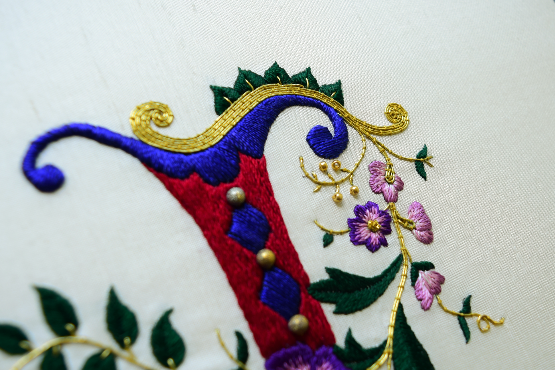 Top view of silk and gold monogram initial with leaves and flowers