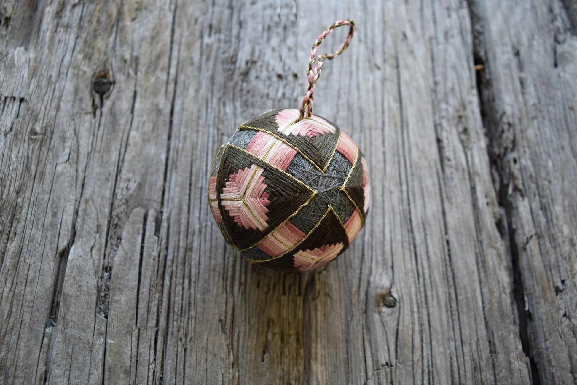 Pink and soft brown temari ball hand embroidered in interlocking pattern