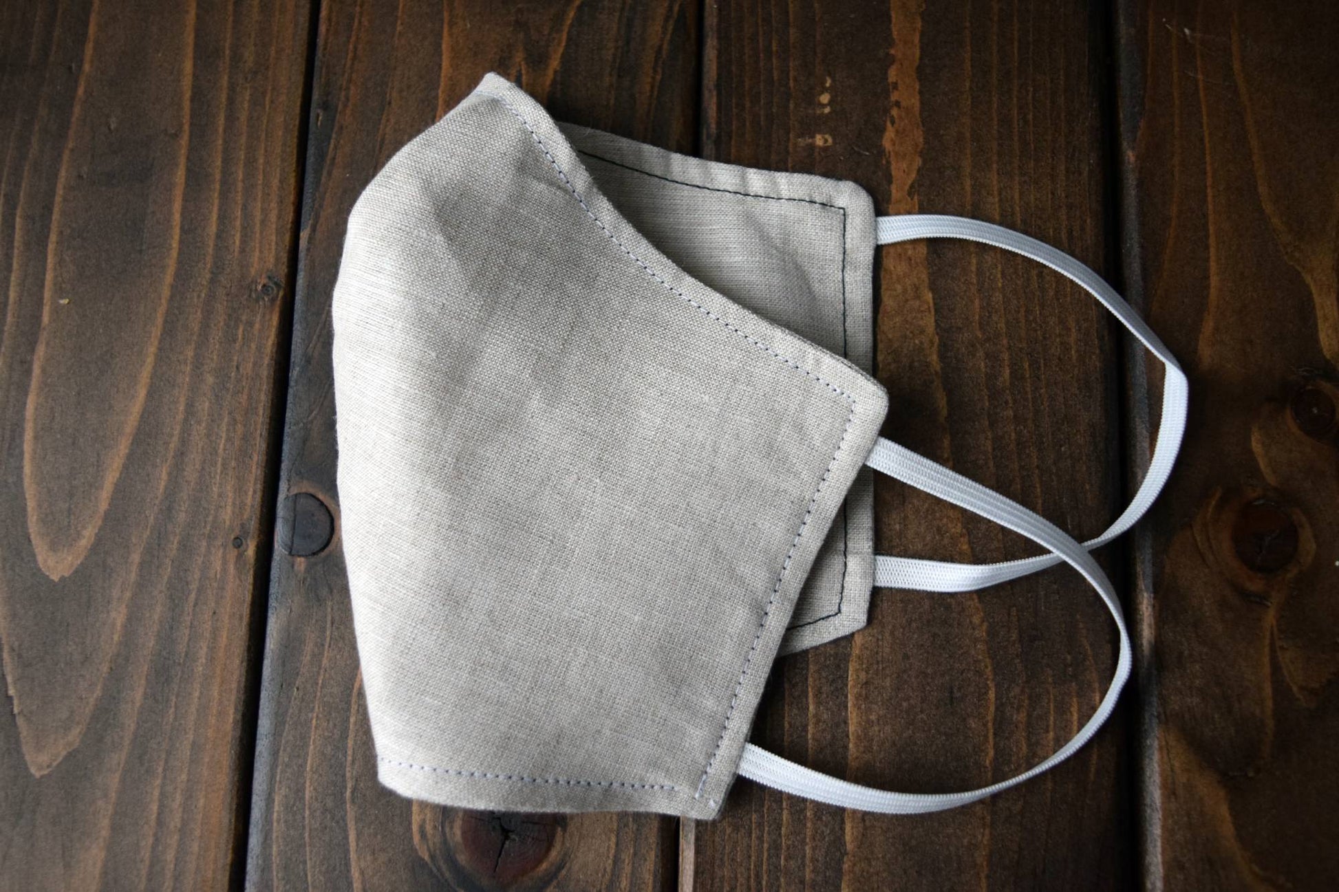 Oatmeal linen face mask folded to show topstitching detail and shape with elastic loops