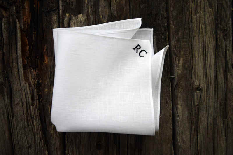 White linen pocket square monogrammed with two initials in black, in upper corner