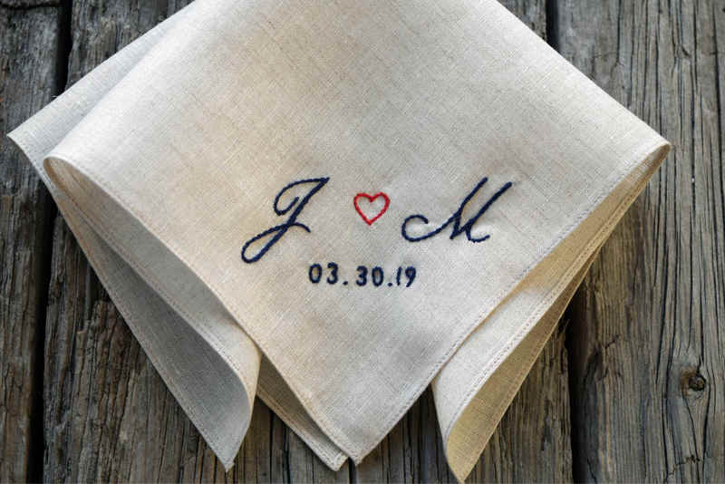 Soft tan handkerchief embroidered with two letters and a small heart in a copperplate script with a wedding date below