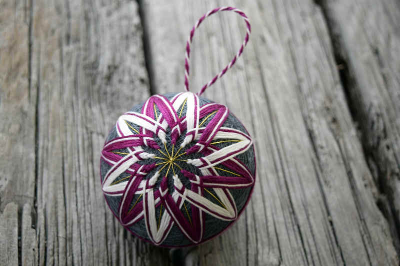 Hand embroidered temari ball in counterchange pattern of red-purple and white on grey with gold marking threads