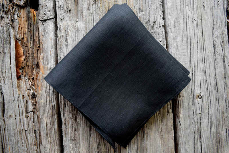 Black Irish linen handkerchief folded in quarters on a weathered wood background