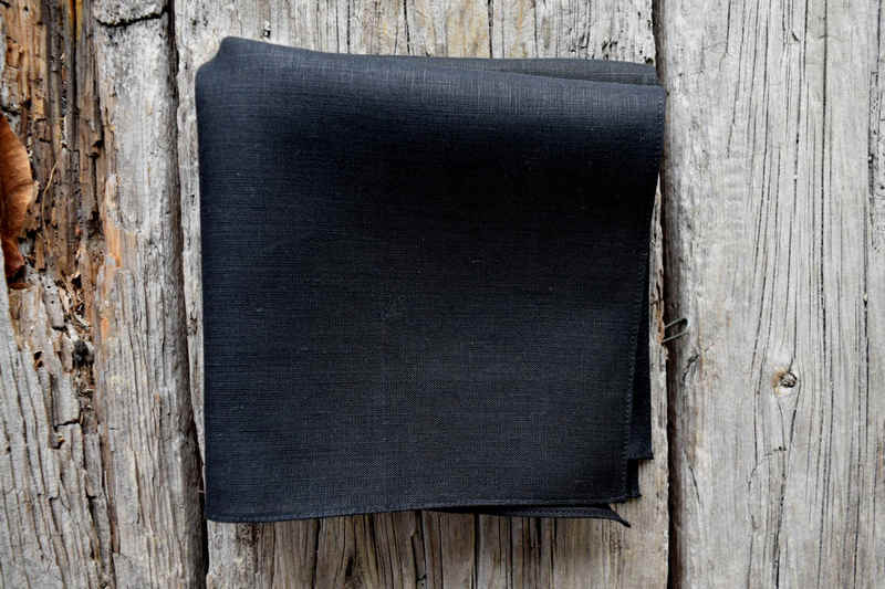 Folded black linen handkerchief on wood background