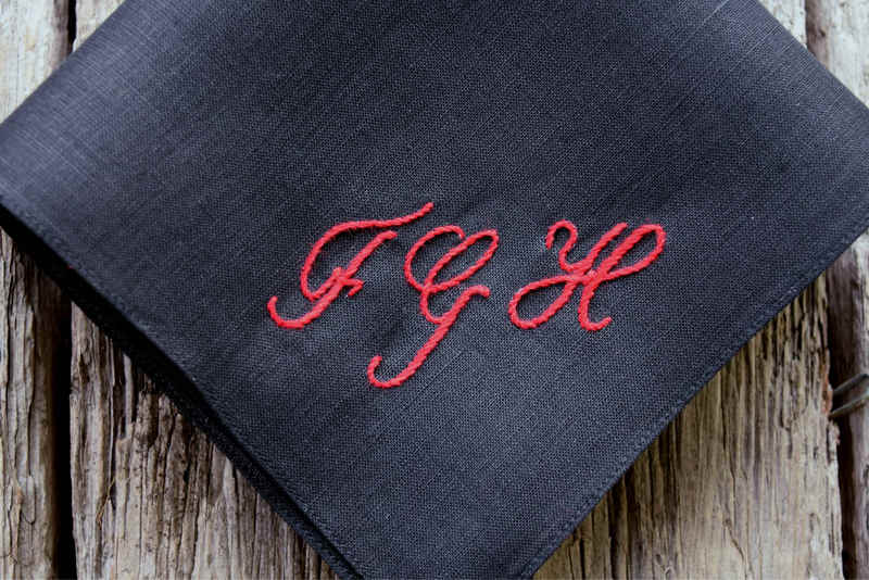 Closeup of black linen pocket square showing personalized monogram FGH in script
