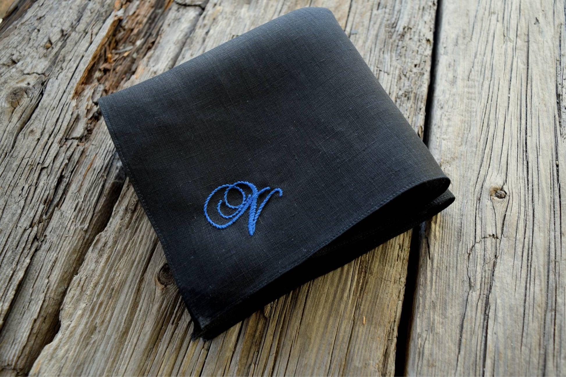 Side view of black Irish linen handkerchief embroidered in an antique script with the letter N in blue