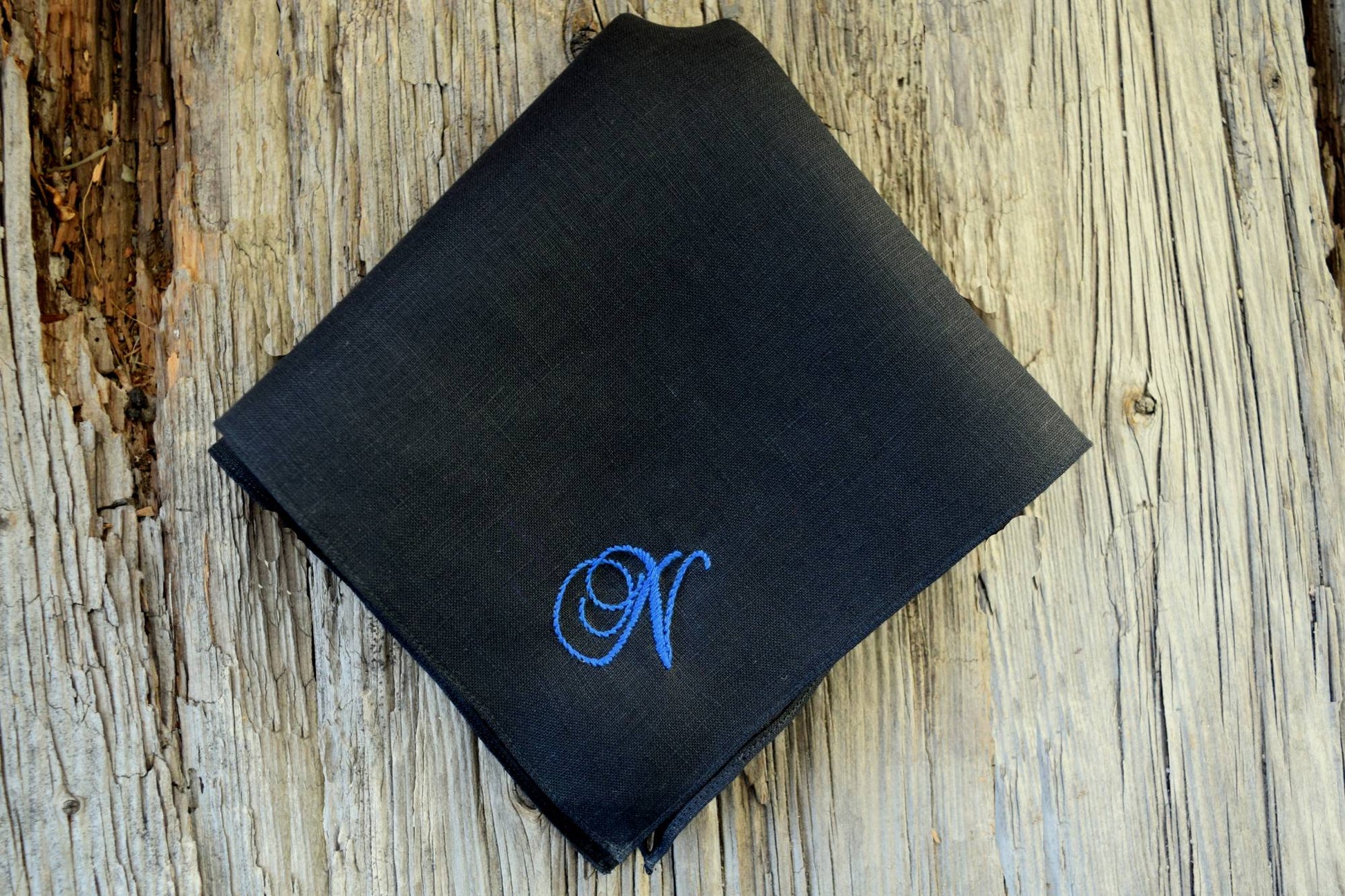 Black linen pocket square hand embroidered with a blue N in a classic script