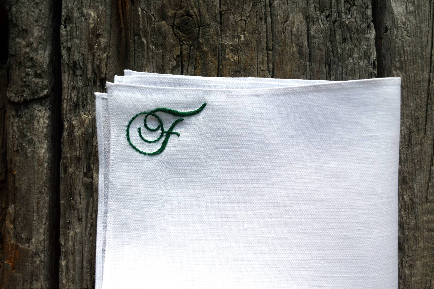 Closeup of hand embroidered linen handkerchief monogrammed with initial F in green