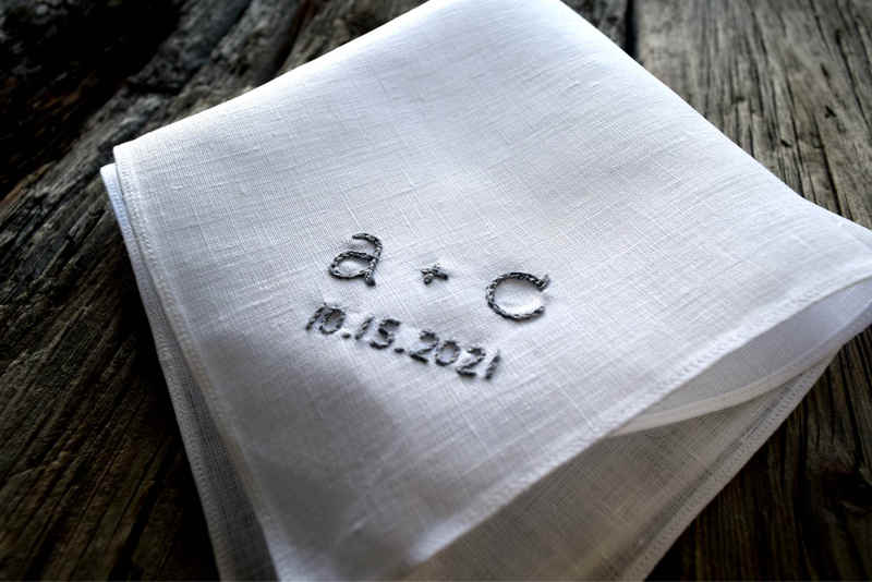 Close up of white linen handkerchief at an angle showing detail of chain stitch letters. Handkerchief reads a + c 10.15.2021