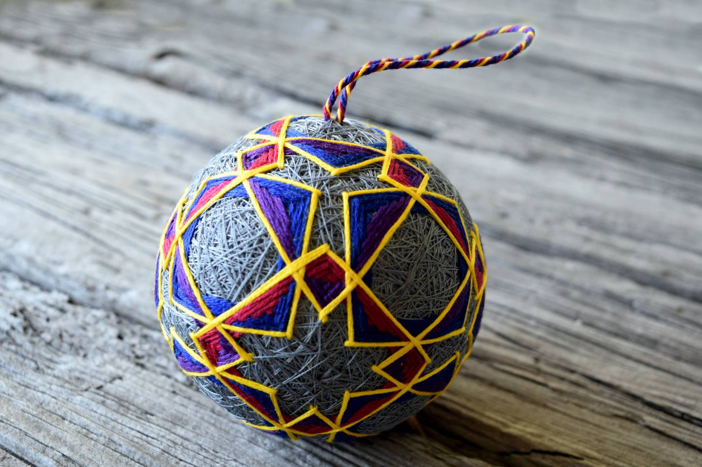 Japanese temari ball in jewel tones hand embroidered in interlocking open pattern