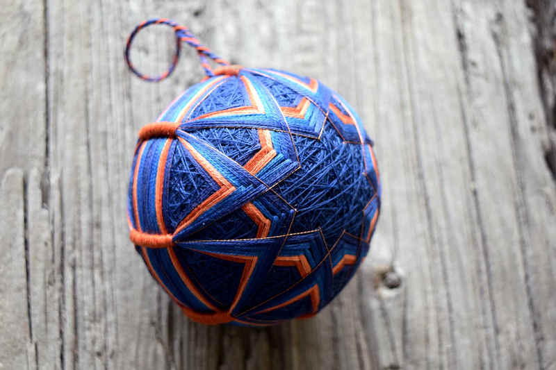 Japanese temari ball Taniki embroidered in star pattern of copper and deep blue with wrapped bands in copper