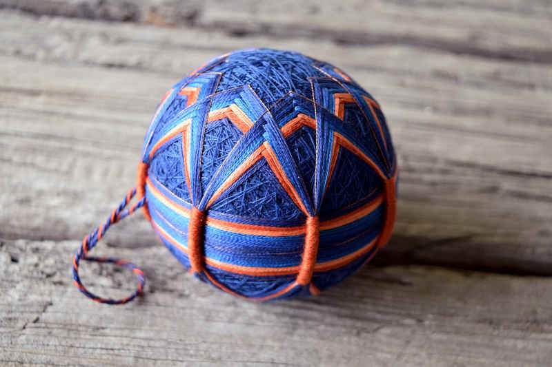 Japanese temari ball in copper and blue showing obi band with wrapped thread bundles