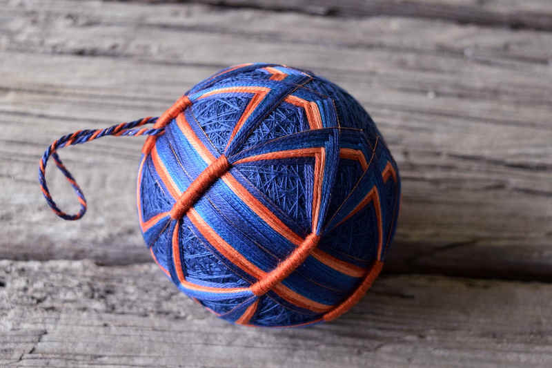 Hand embroidered temari ornament in navy and burnt orange with vaulted design