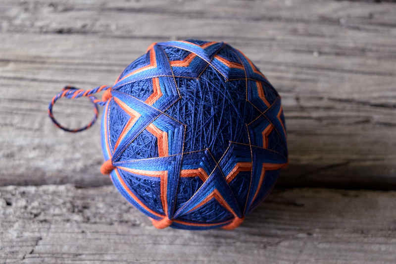 Japanese temari ball 'Taniki' showing eight pointed star design in copper and deep blue