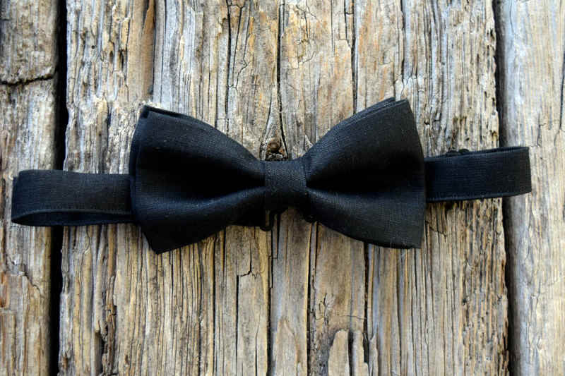 Black Irish linen pre-tied adjustable bow tie shown on weathered wood boards
