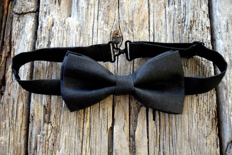 Black linen bow tie on wood background, showing adjustable fittings