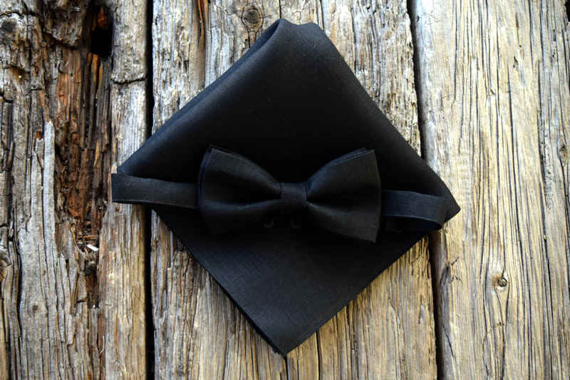 Black linen bow tie, adjustable and pre-tied, on a matching pocket square folded in quarters
