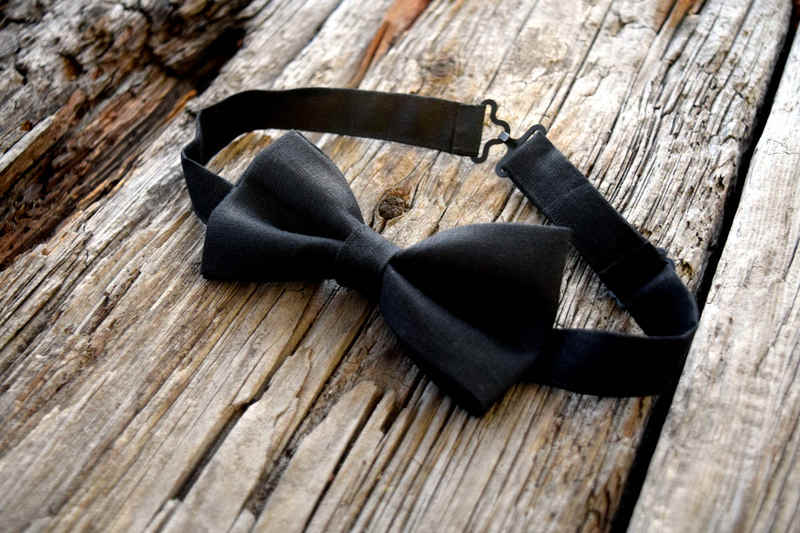 Black Irish linen adjustable bowtie shown against wood background
