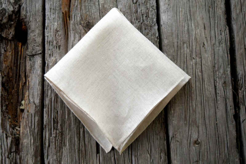 Folded Irish linen handkerchief with hand rolled hem in natural unbleached color