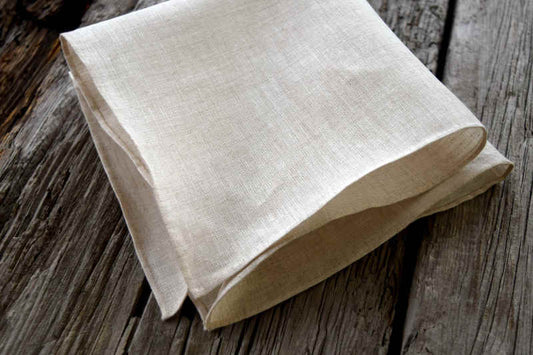Folded Irish linen handkerchief in natural oatmeal color, finished with hand rolled hems