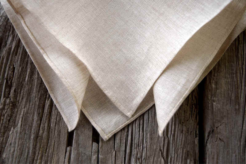 Closeup detail of Irish linen handkerchief with hand rolled hem, showing detail of hem. Handkerchief is in natural oatmeal color.