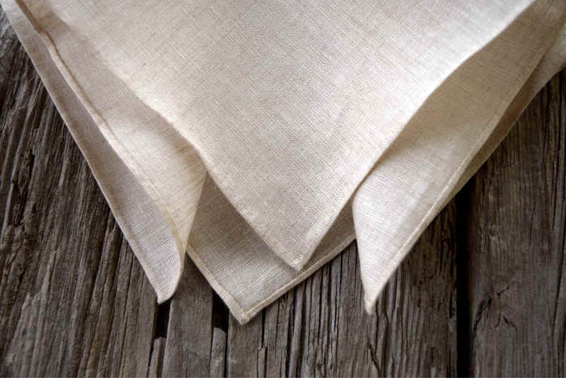 Closeup detail of Irish linen handkerchief with hand rolled hem, showing detail of hem. Handkerchief is in natural oatmeal color.