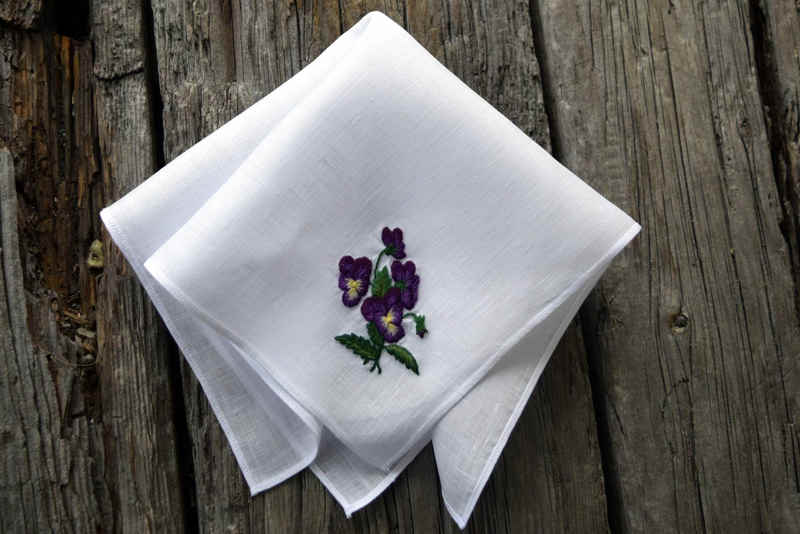 White linen handkerchief hand embroidered with a bouquet of pansies in purple and yellow