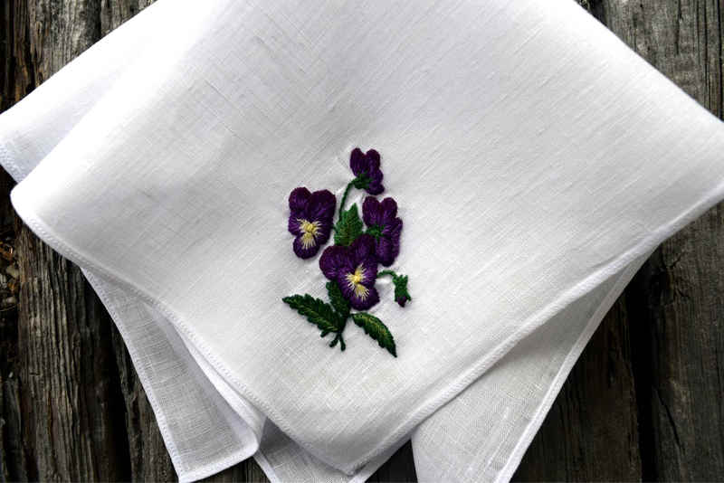 Closeup of white hankie with hand embroidered purple pansy bunch in one corner