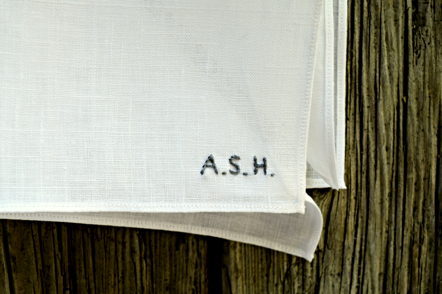 Closeup of white linen pocket square with tiny block letter initials