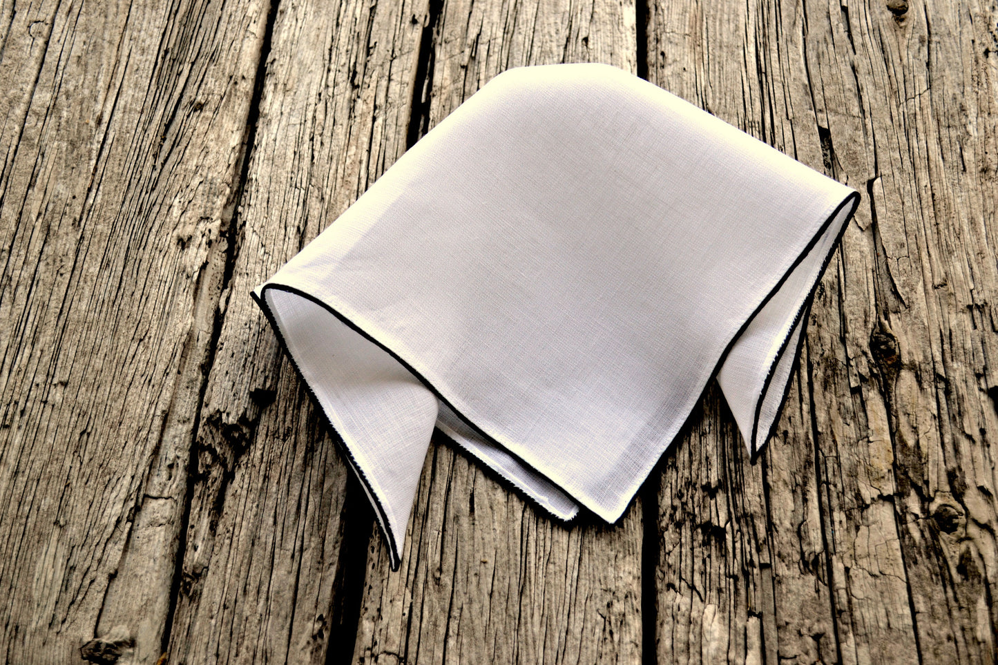 Loosely folded Irish linen pocket square in white with black satin bordered edge