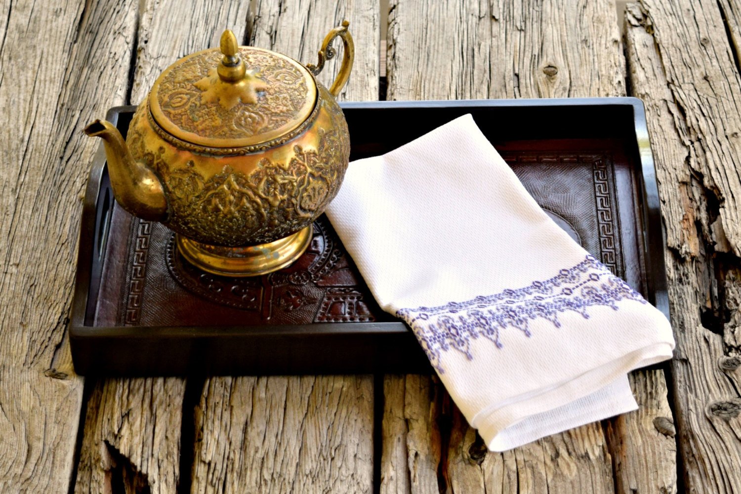 Huck tea towel embroidered in shades of purple on tray with brass teapot