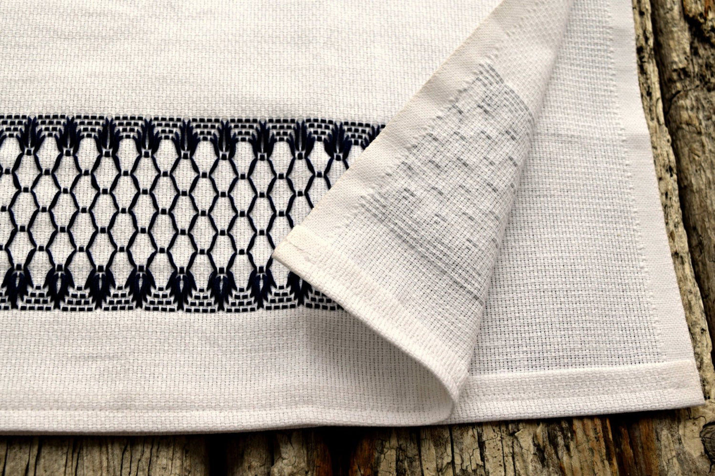 Huckaback dish towel showing front and back of embroidery in navy