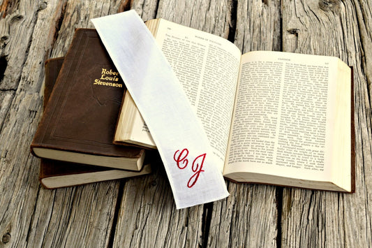 White linen bookmark personalized with monogrammed initials across open book