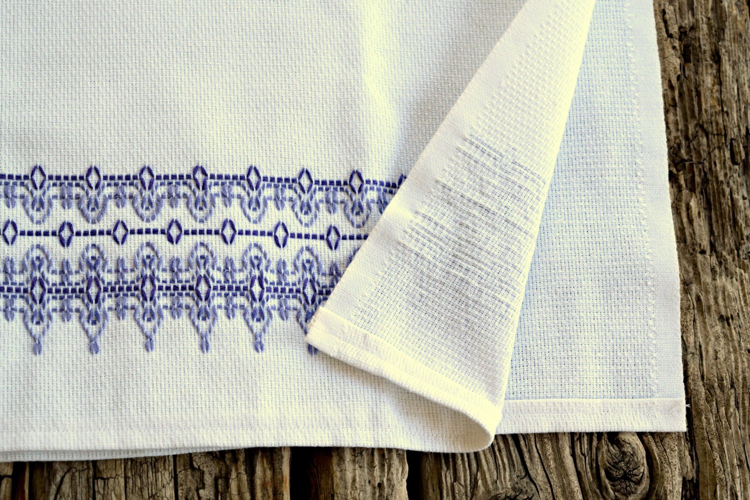 White huck tea towel showing lavender embroidered design on front and no design on back of fabric