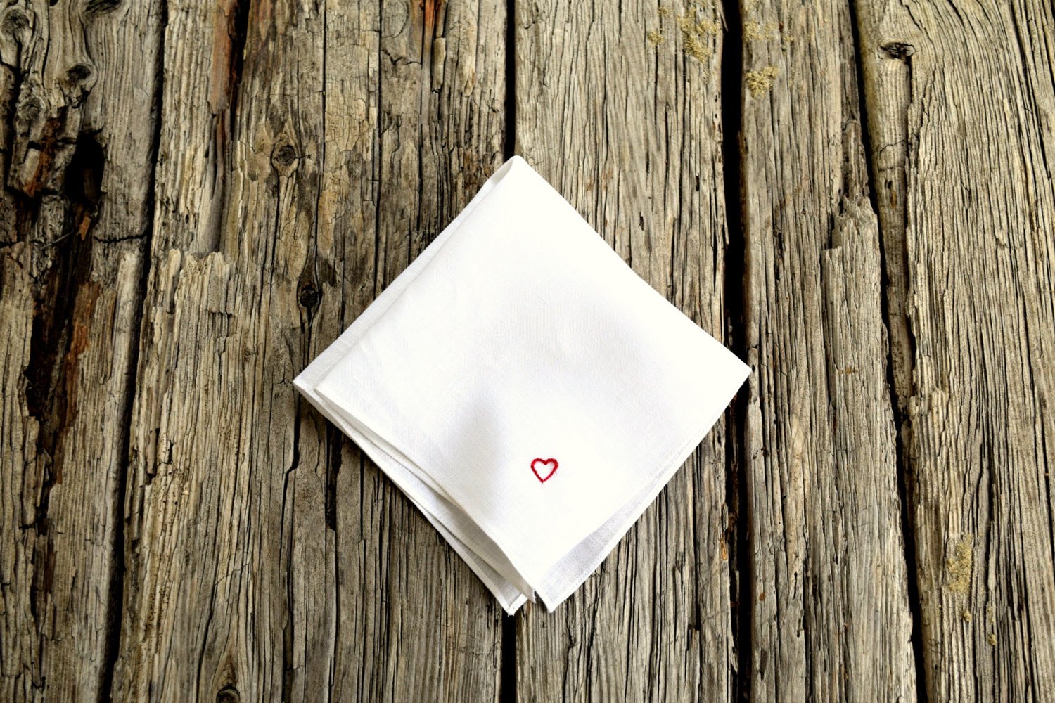 White linen handkerchief hand embroidered with tiny red heart