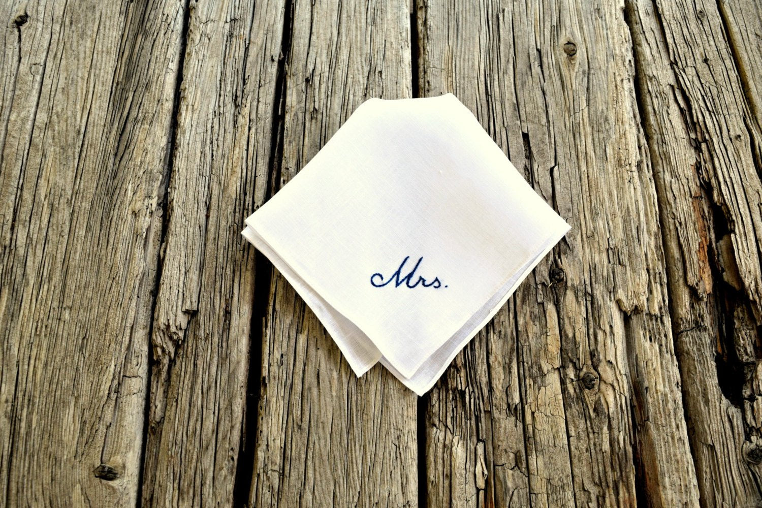 White linen hanky embroidered with Mrs. on wood background