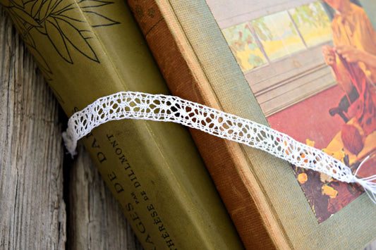 Handmade bobbin lace in white laying across lacemaking books