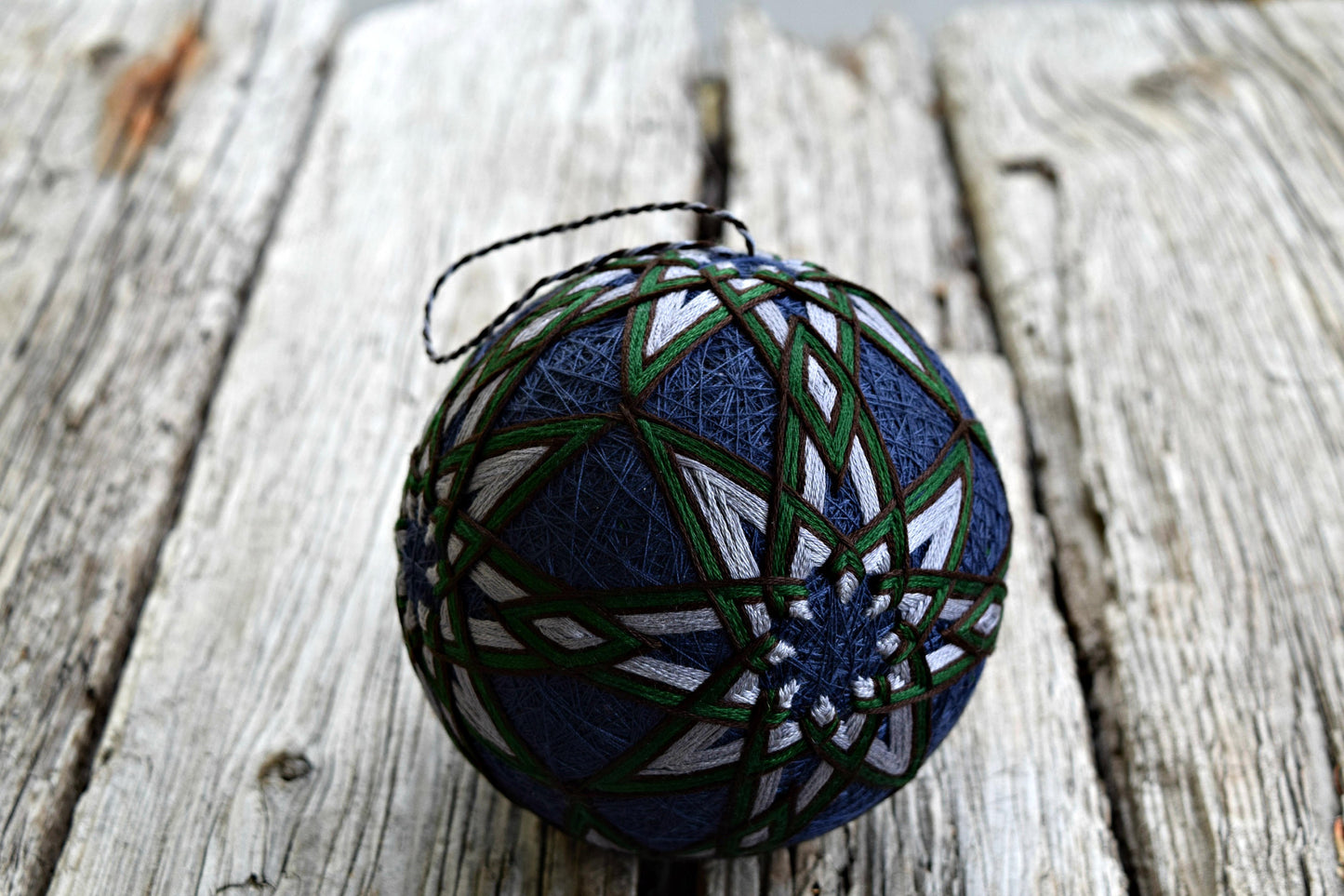 Dark blue temari embroidered in grey, green, and brown stars