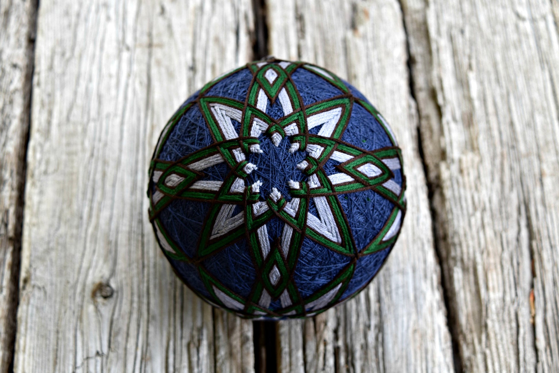 Navy temari ball embroidered with all over kiku design in grey, green, and brown