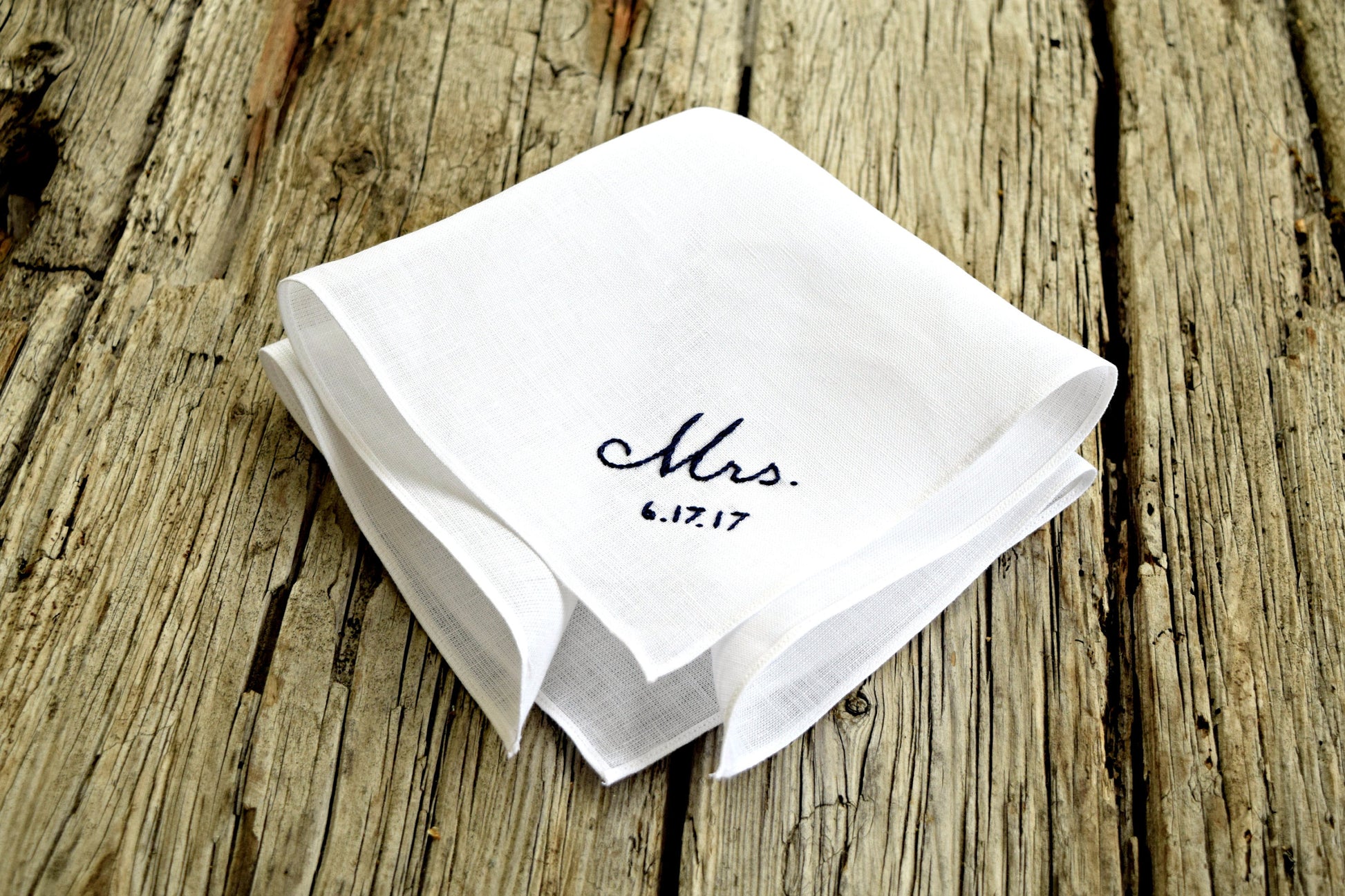 Side view of white linen hanky embroidered with Mrs and wedding date