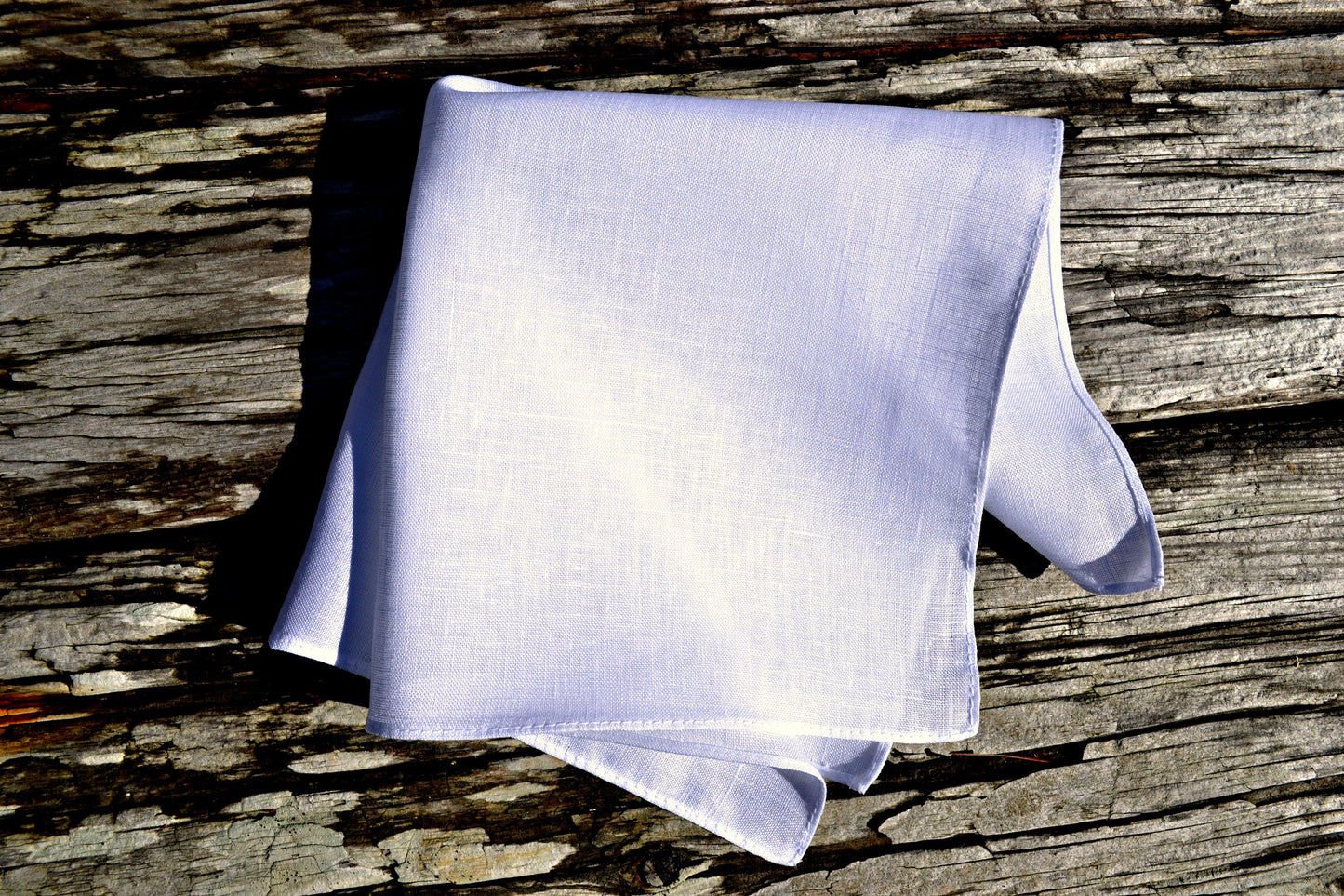 White Irish linen handkerchief with narrow rolled hem on wood background