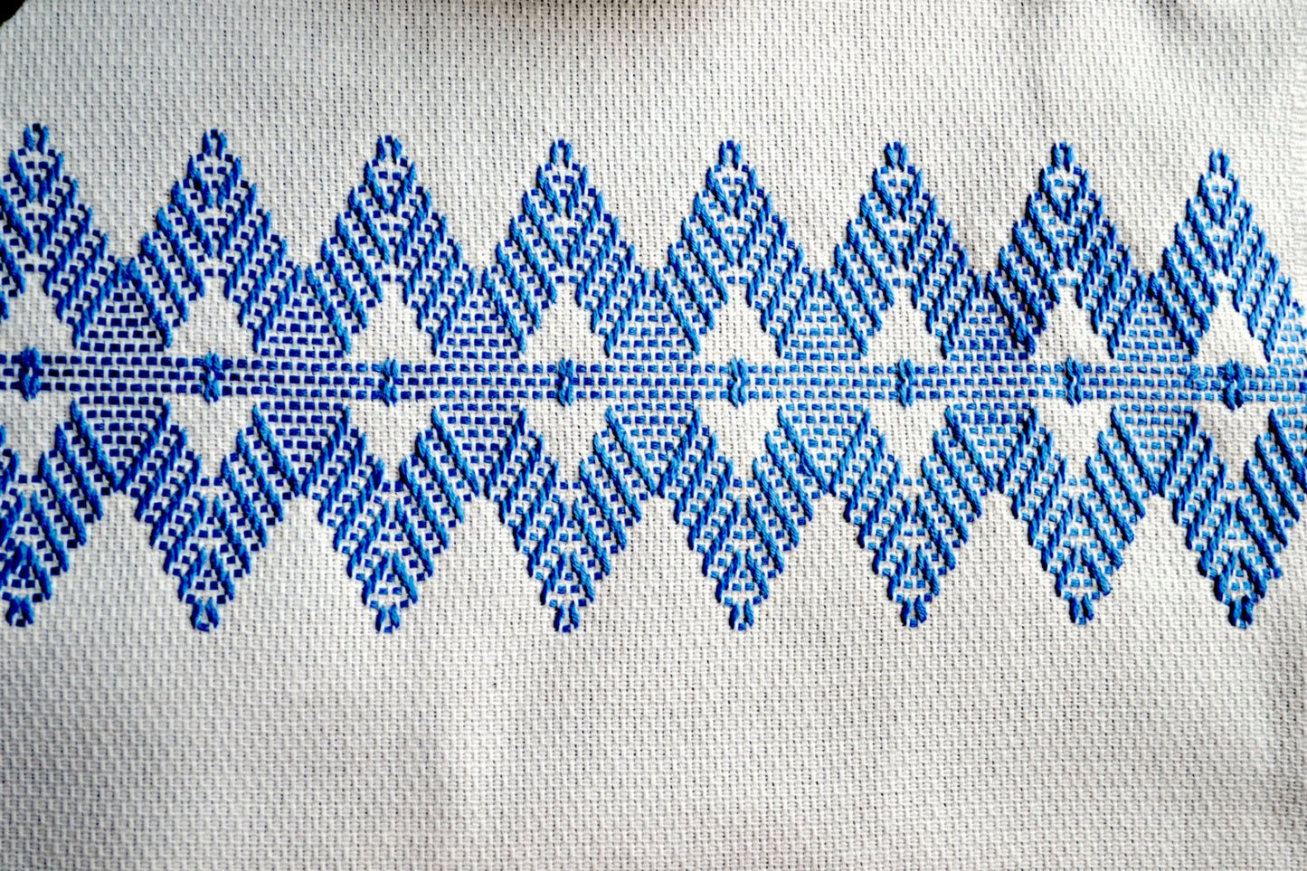 Closeup of blue diamond huck design on white tea towel