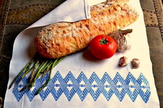 White kitchen towel with blue diamonds wrapping bread, asparagus, tomato and garlic